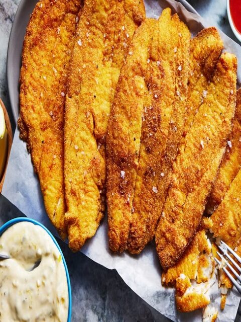 Golden crispy fried fish with fresh lemon and herbs